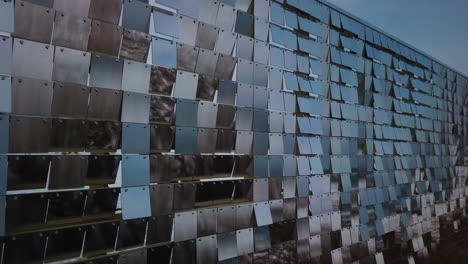 a wall of reflective rows of plexiglass panels moving in tandem with a fast wind, wide shot