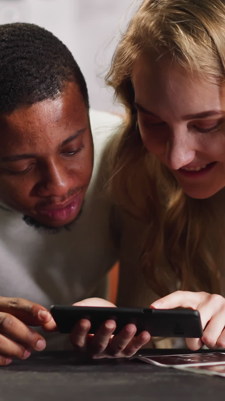 Lovely young couple of African-American man and white girlfriend tries to detect baby gender on ultrasound record in living room slow motion
