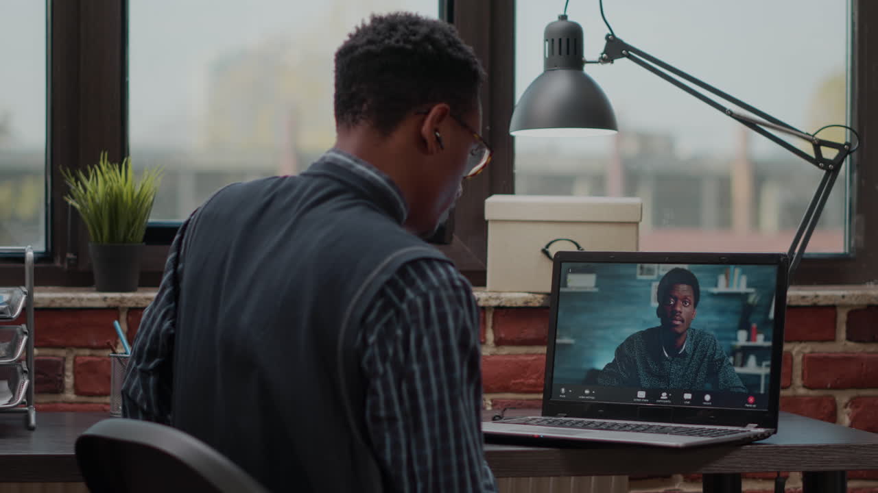 Startup employee using remote video call on laptop to talk to colleague