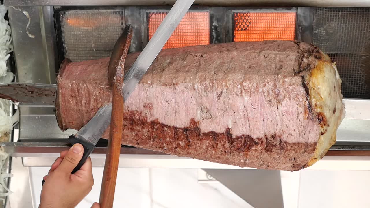 Carving Döner Kebab Meat from a Vertical Rotisserie