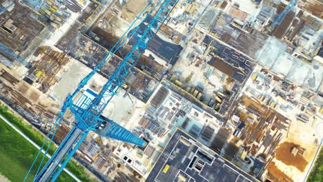 aerial bird eye view of a construction site building cranes looking down industrial machinery area around residential urban apartments