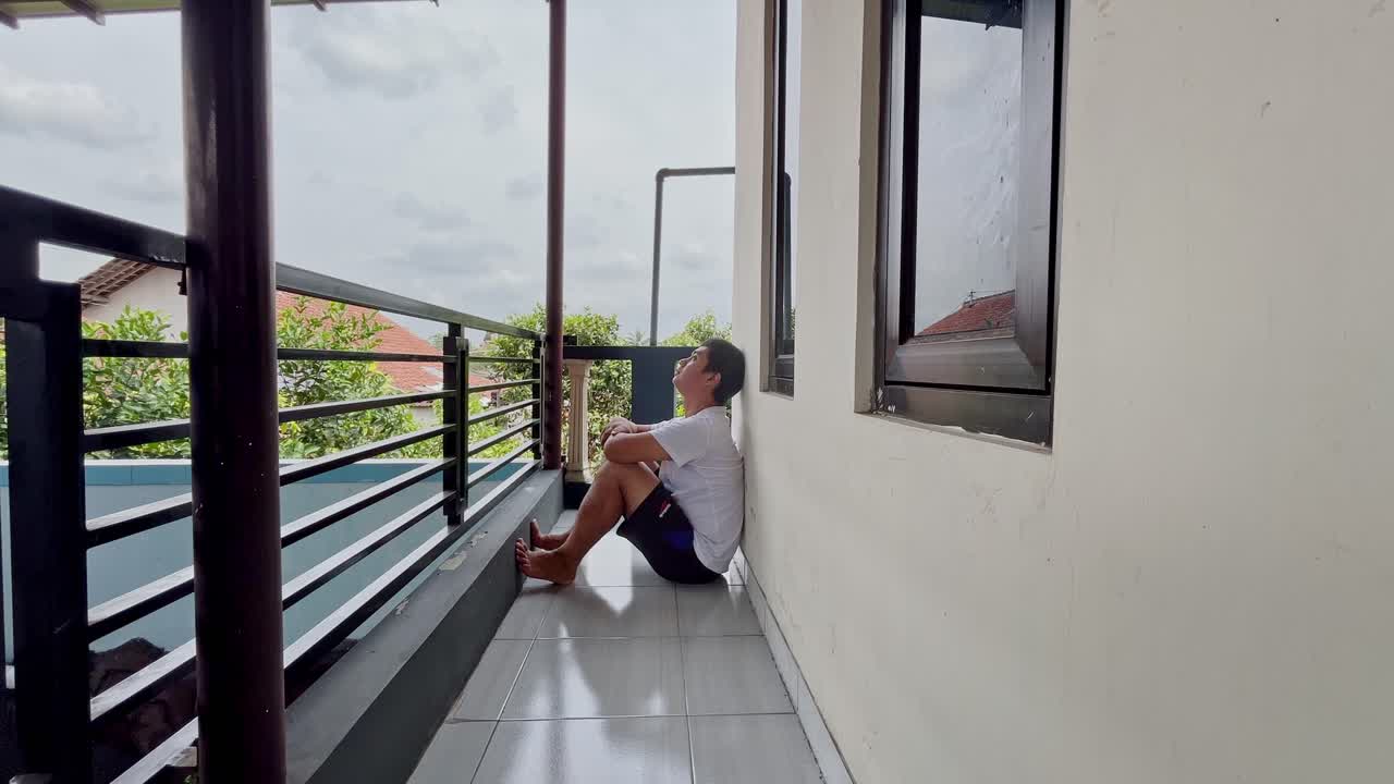 un hombre sentado solo en el suelo apoyado en la pared