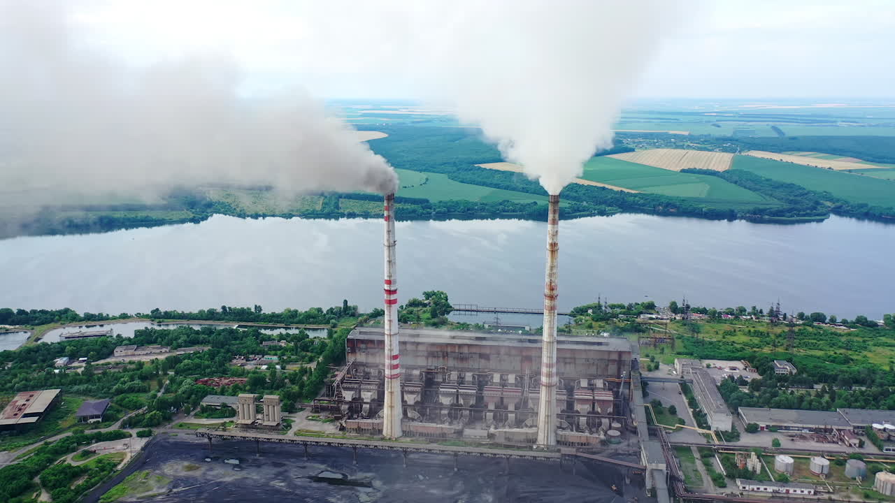 Harmful industry on river background. Factory pipes with smoke pouring into the atmosphere. Air pollution among beautiful nature.