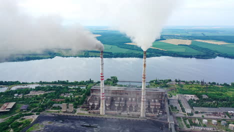 harmful industry on river background. factory pipes with smoke pouring into the atmosphere. air pollution among beautiful nature.