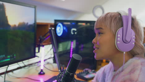 woman gaming at home sitting at desk wearing headphones for live stream