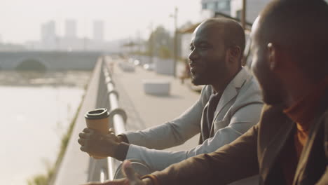 african american businessmen chatting on embankment in city