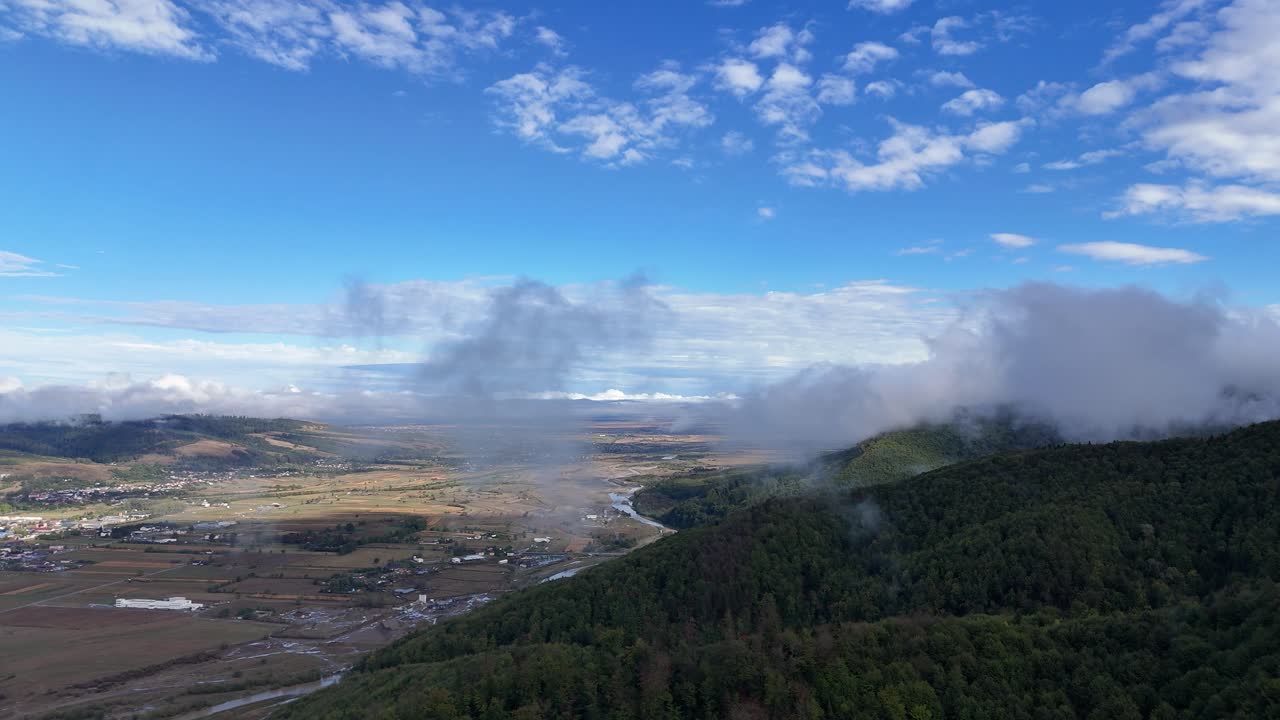 Drone passing through a cloud near Gura Humorului city, showcasing the river and forested trees