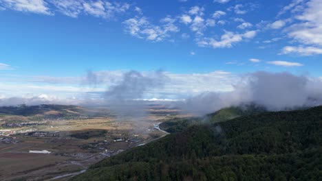 drone passing through a cloud near gura humorului city, showcasing the river and forested trees