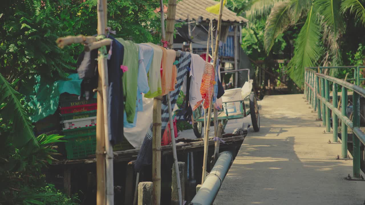 Laundry Hanging on Bamboo Poles Beside a Canal-side Walkway in Bangkok, Thailand - Static Shot