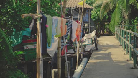 laundry hanging on bamboo poles beside a canal-side walkway in bangkok, thailand - static shot