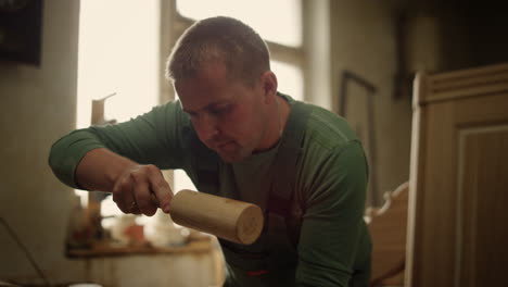 hombre serio decorando productos de madera en interiores. trabajador de madera usando herramientas en el estudio