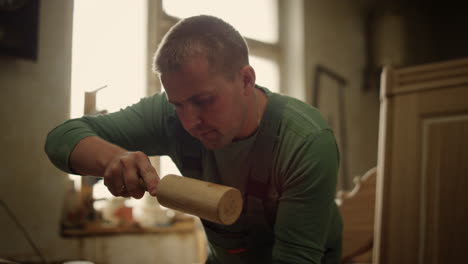 serious man decorating wooden product indoors. wood worker using tools in studio