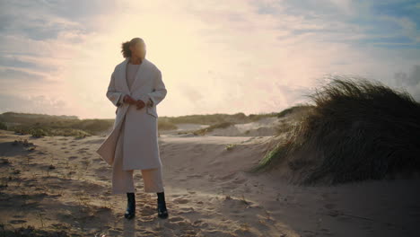 woman resting sand dunes posing in sunlight. stylish african american admiring