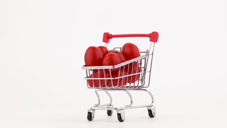 el carrito del supermercado lleno de tomates de cereza roja. girando en la mesa giratoria. aislado en el fondo blanco. primer plano. macro.