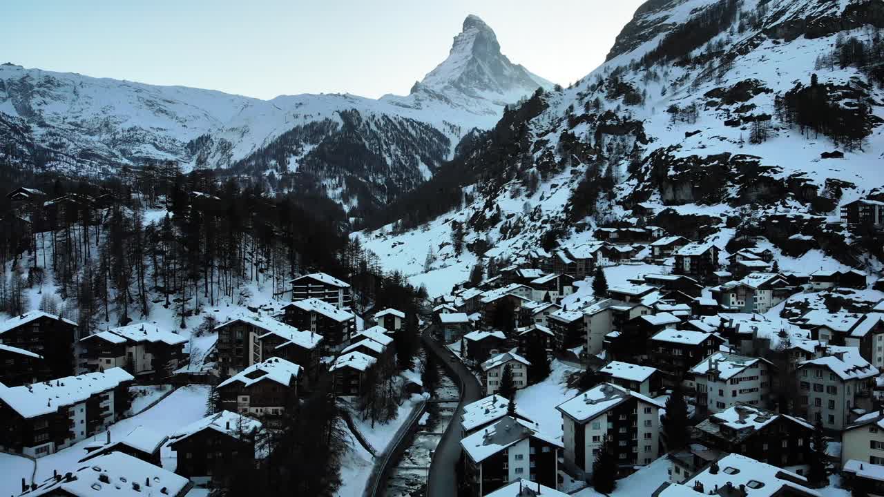sobrevuelo aéreo sobre el centro de la ciudad de zermatt durante el invierno con vistas al matterhorn, los tejados y el río