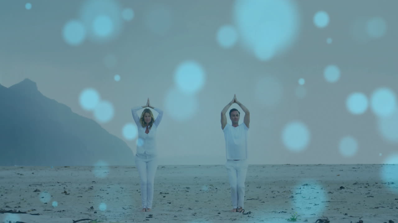 해변에서 요가를 연습하는 백인 부부 위의 빛의 점의 애니메이션