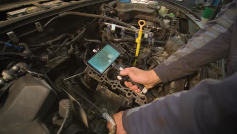 manos de mecánico de automóviles comprobar el motor del vehículo con endoscopio técnico con cámara rotativa y teléfono móvil. reparación de la cabeza del motor y las válvulas.