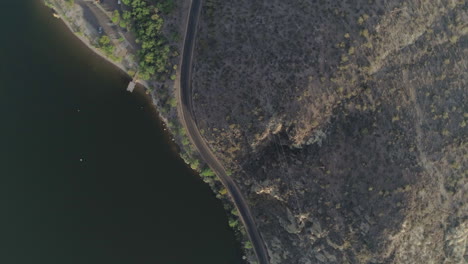 AERIAL---Spiral-Shot-of-Desert-Road-Near-Lake