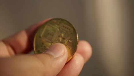 a close-up of an individual flipping a commemorative golden thai baht coin