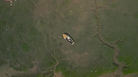 old derelict boat, slow circle down to close up over river tide plain