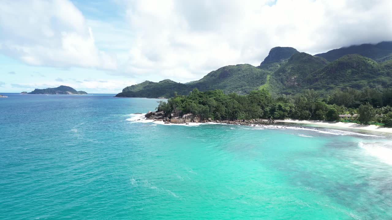 Drone shot flying over bright blue water of the seychelles tropical islands