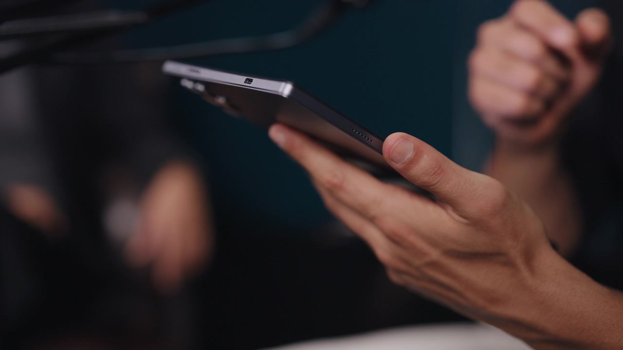 Detailní záběr osoby používající chytrý telefon v tlumeně osvětleném prostředí