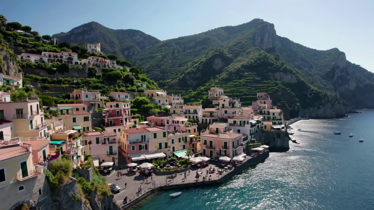 Aerial video captures a picturesque coastal village with colorful buildings and lush hills