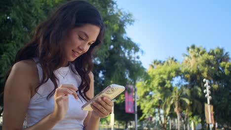 Asiatisches-Mädchen-Scrollt-Foto-Auf-Smartphone.-Lachende-Frau,-Die-Auf-Den-Telefonbildschirm-Schaut