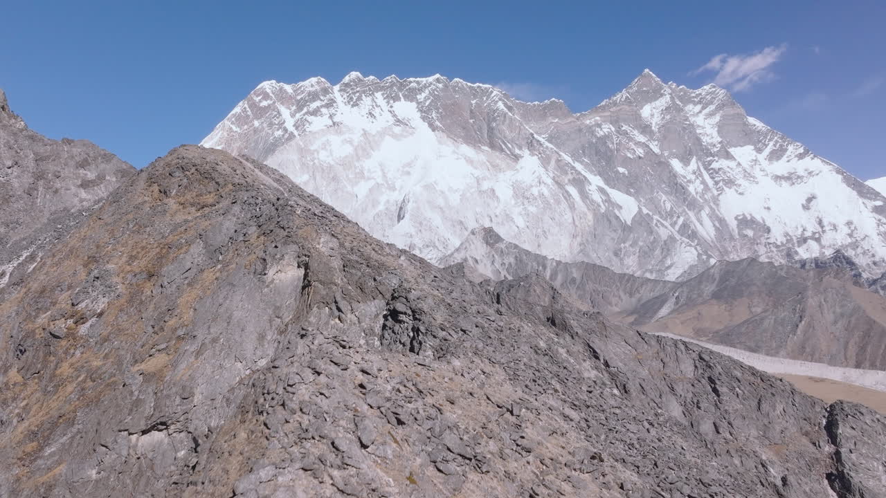 Ripresa aerea con drone del picco Nangkartshang lungo il trekking del Campo Base Everest in Nepal. Montagne himalayane innevate e terreno roccioso accidentato con vista verso imponenti vette di 8000 metri.