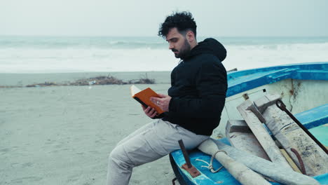 man on the beach in winter re reads his notes sitting on a boat