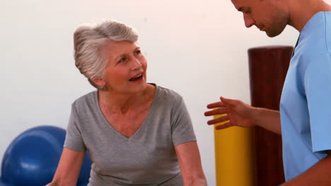 physiotherapist helping patient walk with parallel bars