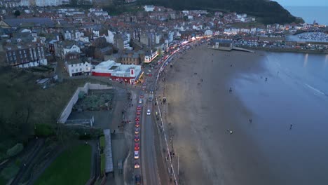 Avión-Teledirigido-Inclinado-Hacia-Abajo-Sobre-Playas-De-Arena-A-Lo-Largo-De-La-Ciudad-De-Scarborough-En-North-Yorkshire,-Inglaterra,-Reino-Unido-Durante-La-Noche