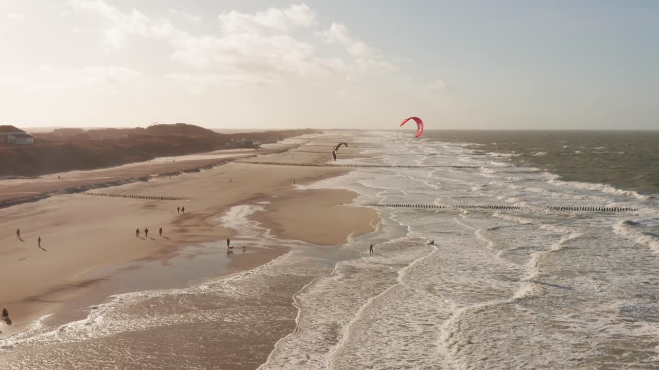 Kitesurfers waiting and talking on the beach during a cold windy winter day. Drone shot