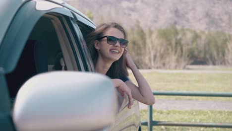 cheerful-girl-talks-with-friend-in-car-at-rural-site-closeup