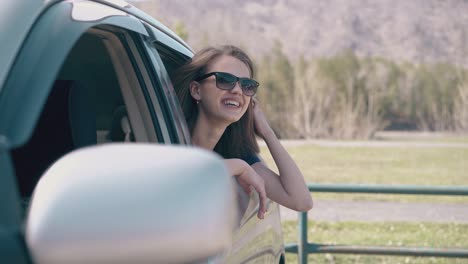 chica alegre habla con un amigo en el coche en el sitio rural de acercamiento