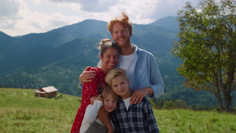 Familia-Sonriente-De-Pie-En-Una-Colina-Abrazándose-De-Cerca.-Padres-Felices-Posando-Con-Niños