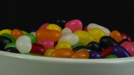 close-up view: jelly beans pile up in revolving bowl in dark room