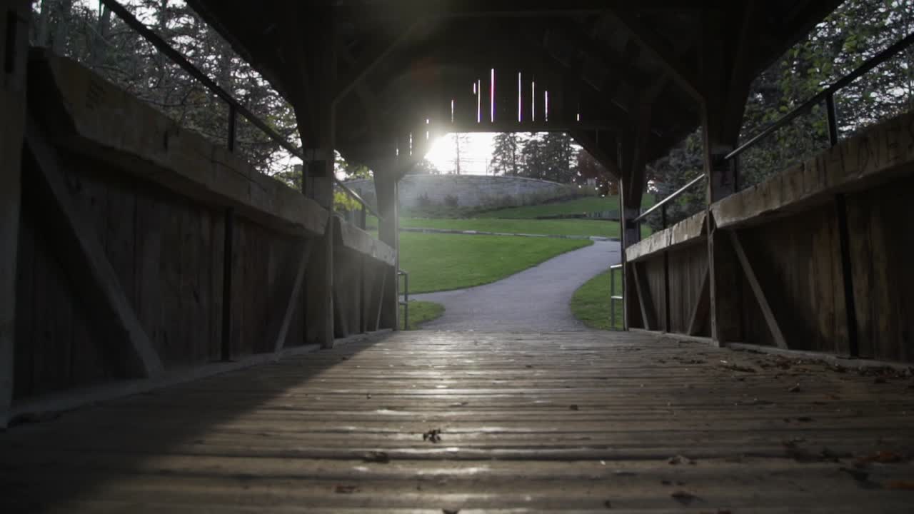 puente peatonal de madera con luz solar que pasa a través del techo de madera en whitby, canadá