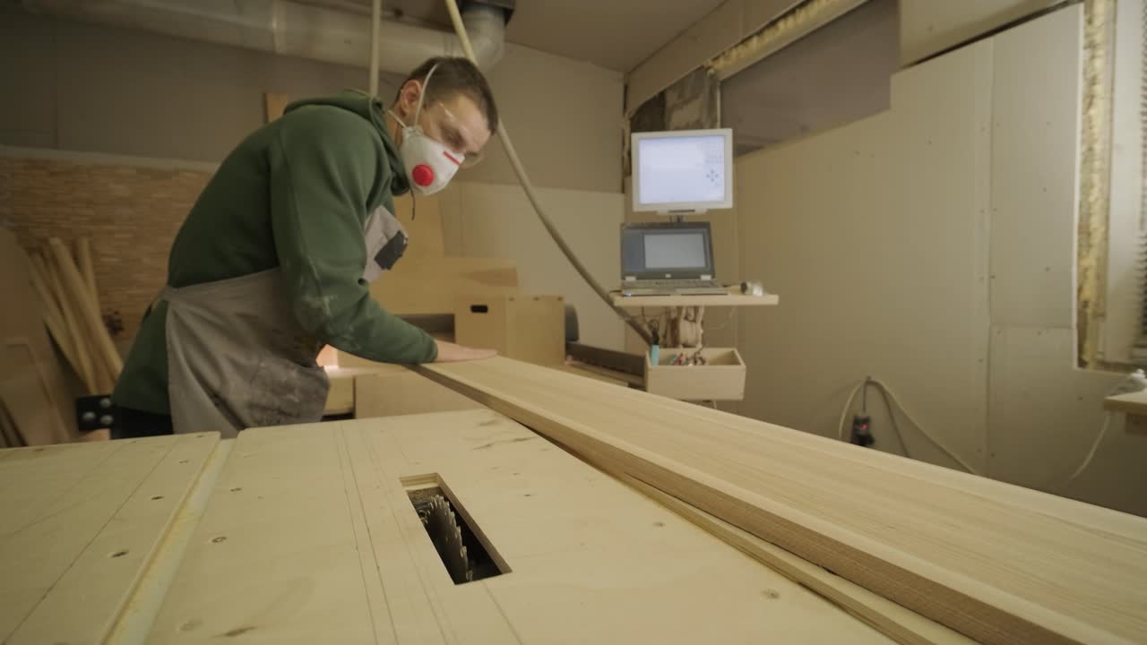 trabajador de la madera profesional en máscara y gafas comprueba la madera en bruto, tabla de madera, panel de contrachapado