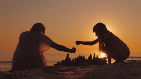 mother plays with her daughter on the beach together they build a castle made of sand 4k video