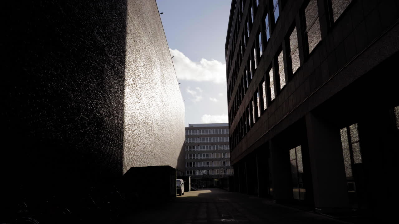 독일 른의 평화로운 도시 골목으로, 빛과 대조적인 그림자를 반사하는 질감 벽으로 현대적인 건축을 선보이고 있습니다.