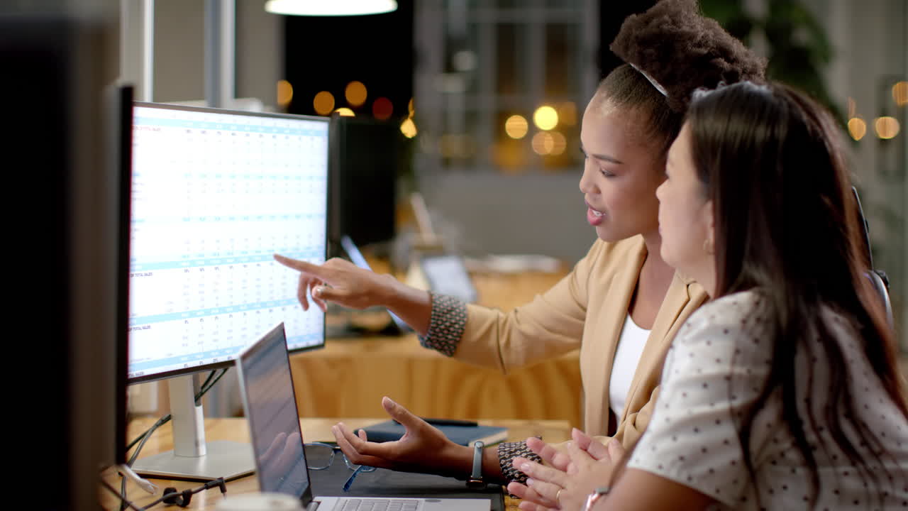 Young African American woman and biracial woman collaborate in a business office