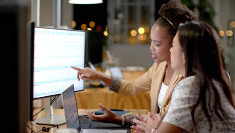 young african american woman and biracial woman collaborate in a business office