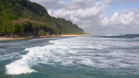 Niedrige-Vorwärtsantenne-Von-Meereswellen-Durch-Hohe-Bewaldete-Klippen-In-Indonesien