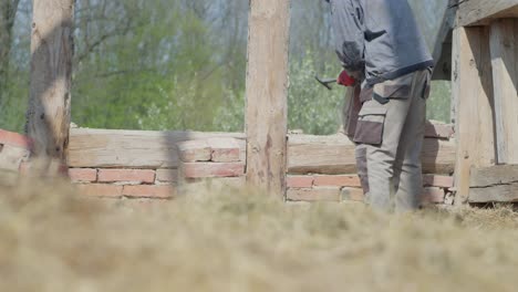 worker use hammer to clean bricks from mortar while deconstructing old house