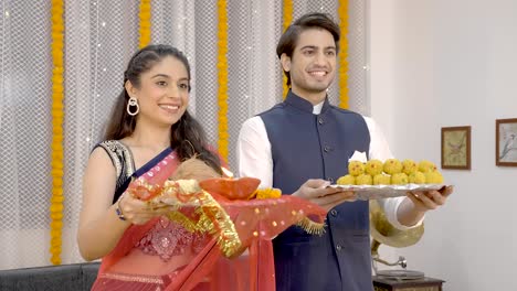 indian couple wishing happy diwali with sweets and pooja thali