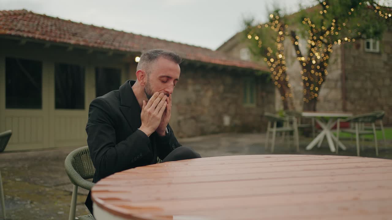 frustrated man in black suit slams table in outdoor emotional breakdown