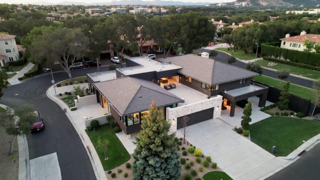 Launching drone pulling back over two-story suburban house at dusk, showing roof deck and area