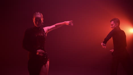 una pareja de salón de baile actuando con un programa latino. una pareja bailando en una sala oscura.
