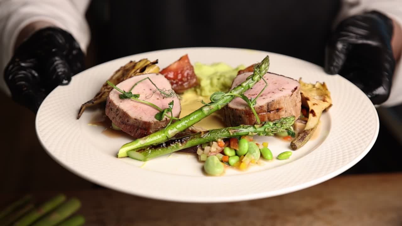 Koki Menyajikan Hidangan Tenderloin Babi Adiboga yang Tertata dengan Asparagus
